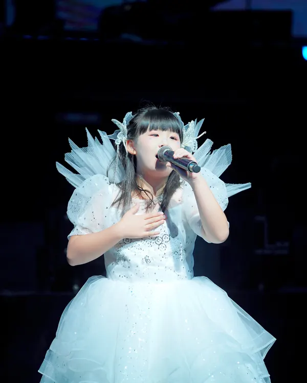 身穿白色演出服的星童声学员在演唱